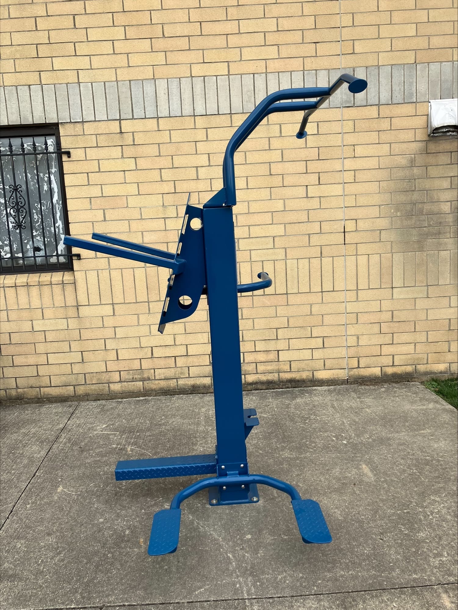 Heavy-duty prison exercise equipment mounted in an open-air inmate yard.